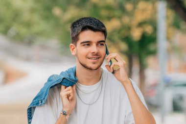 Sokaktaki genç adam cep telefonu ya da akıllı telefonuyla konuşuyor.