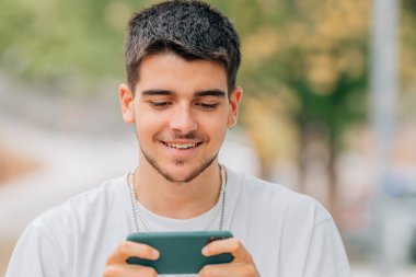 Sokakta oynayan genç adam akıllı telefonuyla oynuyor.