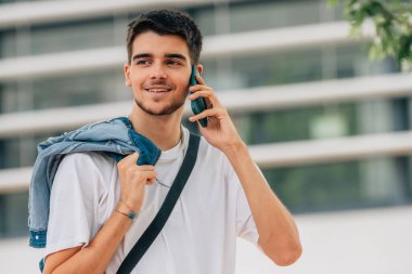 Cep veya cep telefonuyla yürüyen genç adam ya da öğrenci