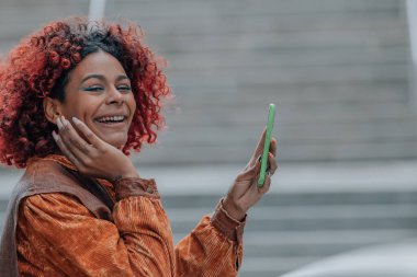 Cep telefonu ve afro saçlı, sokaktaki profil kızı.