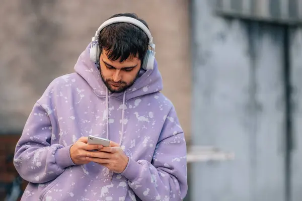 urban young man with mobile phone or smartphone and earphones in the street
