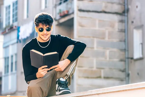 young man reading with textbook outdoors