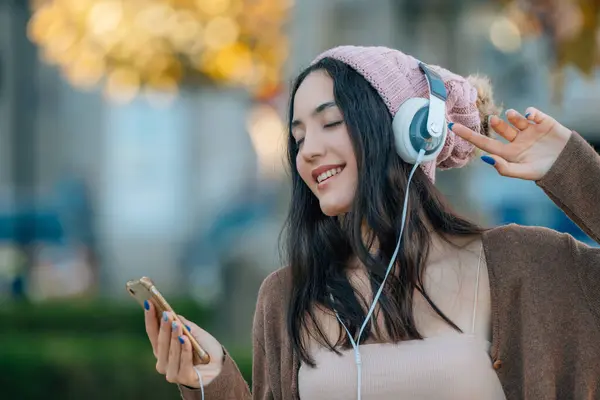 girl with headphones and phone dancing in the street