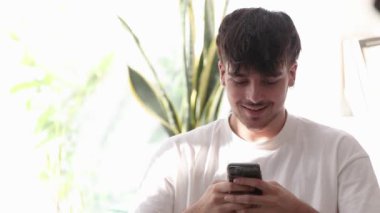 Genç adam evde cep telefonu ya da akıllı telefon ile yazarak sürpriz yapıyor.