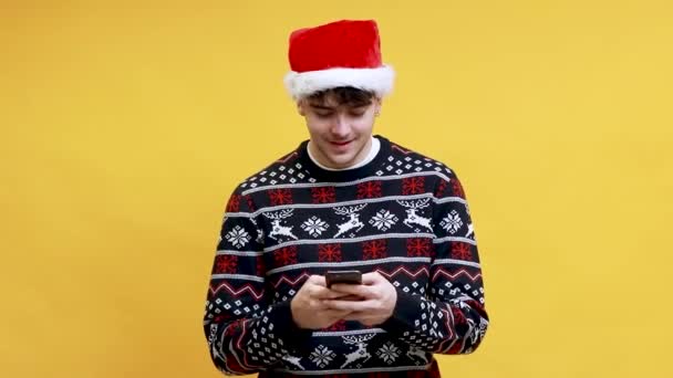 Biały Młody Człowiek Noszenie Santa Claus Kapelusz Wpisując Telefonu Komórkowego — Wideo stockowe