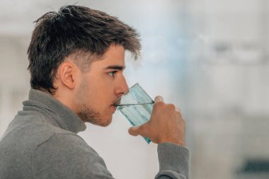 Genç adam bir bardak su içiyor.