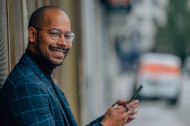 Sokakta cep telefonu olan orta yaşlı Latin bir adam.