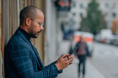 Sokakta cep telefonu olan orta yaşlı Latin bir adam.