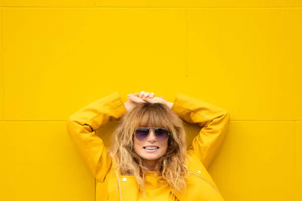 黄色い壁で通りのリラックスした笑顔の大人の女性 ロイヤリティフリーのストック写真