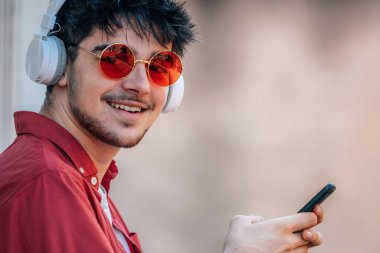 Cep telefonu ve kulaklığı olan genç bir erkek.