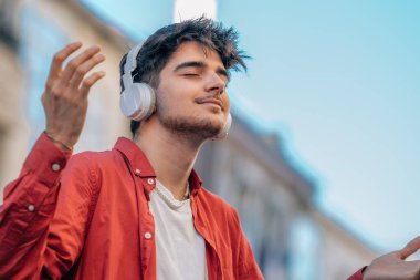 Kulaklıklı genç adam müzik dinlemekten zevk alıyor.