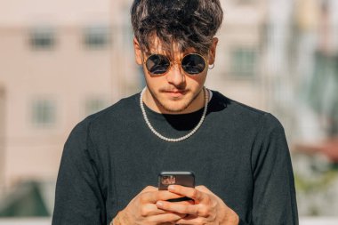 Sokakta cep telefonu ya da akıllı telefonu olan genç bir adam ya da öğrenci