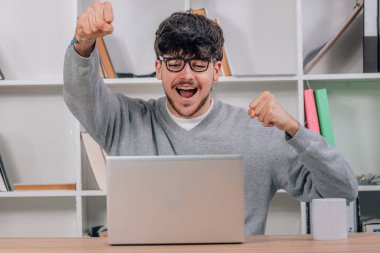 Öğrenci masadaki dizüstü bilgisayarla mutluluktan heyecanlanıyor