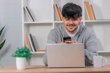 Masasında cep telefonu ve bilgisayarı olan bir öğrenci