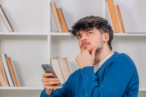 Fiatal Férfi Diák Mobiltelefonnal Vagy Okostelefonnal Kétségek Kifejezésével Stock Kép