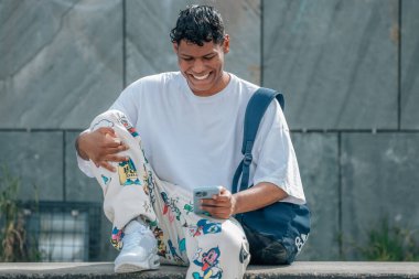 Sokakta cep telefonu olan genç Latin bir adam.