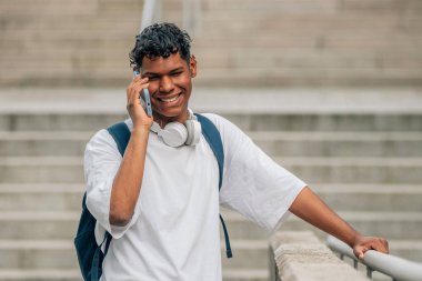Sokakta cep telefonu ya da akıllı telefonla konuşan genç Latin bir erkek.