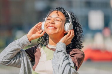 Sokakta kulaklıkla dans eden Latin kız.