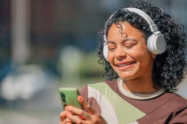 Kulaklığı ve cep telefonu olan bir kız.