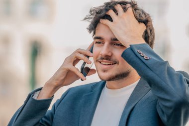 Sokaktaki genç adam cep telefonuyla konuşuyor.