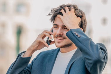 Sokaktaki genç adam cep telefonuyla konuşuyor.