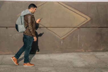 Sırt çantalı ve cep telefonlu genç adam.