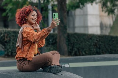 smiling girl with mobile phone on the street in autumn clipart