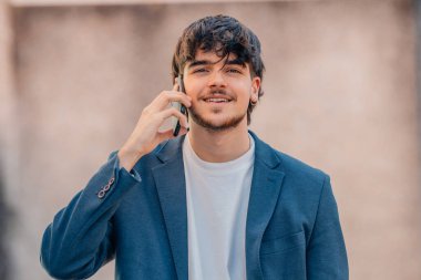 Genç adam dışarıda cep telefonuyla konuşuyor.