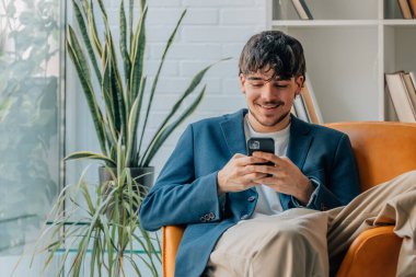 young man sitting with mobile phone or smartphone clipart