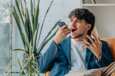 Genç adam cep telefonuyla konuşuyor ve elleriyle konuşuyor.