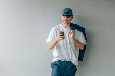 Cep telefonuna bakan şapkalı genç bir erkek portresi