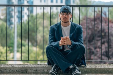 Erkek ya da öğrenci sokakta oturuyor.