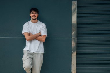 Sokaktaki genç adam duvara yaslanıyor.