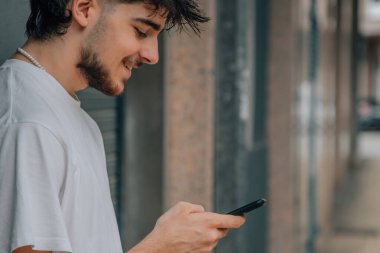 Sokaktaki genç adam cep telefonuna bakıyor.