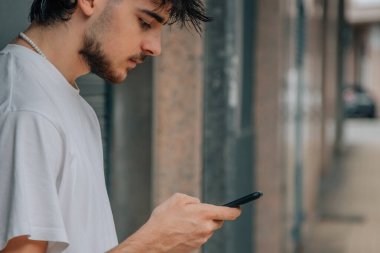 Sokaktaki genç adam cep telefonuna bakıyor.