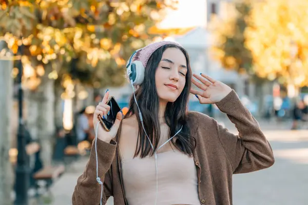 stock image girl with headphones dancing on the street in autumn