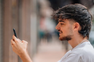 Sokakta cep telefonuna bakan genç adamın portresi.