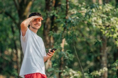 Ormanda cep telefonu olan genç bir sporcu