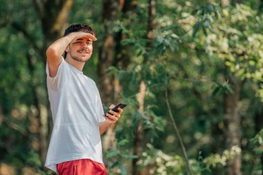 Ormanda cep telefonu olan genç bir sporcu