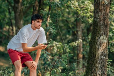 Ormanda cep telefonu olan genç bir sporcu