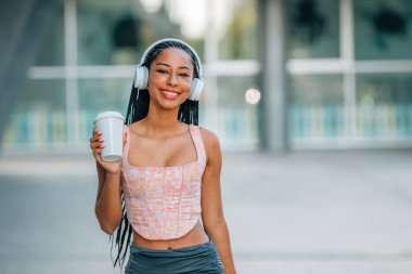 girl on the street with headphones and cup of coffee clipart