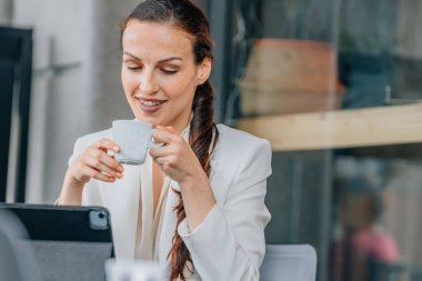 İş kadını laptopla kahve içiyor.