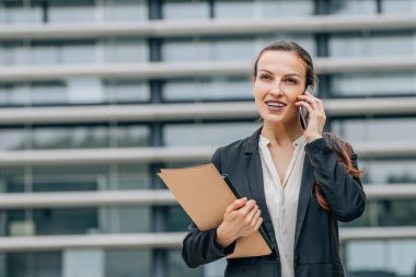Telefonda konuşan bir iş kadınının açık hava portresi.
