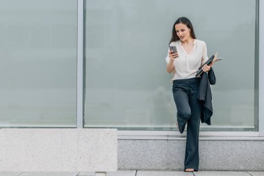 Sokakta cep telefonu ve belgeleri olan bir iş kadını.