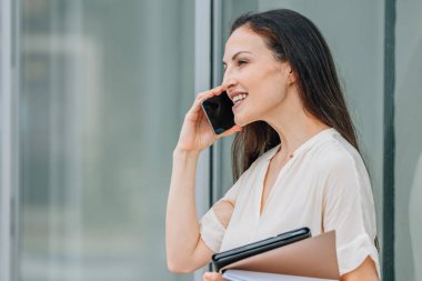 Sokakta cep telefonu ve belgeleri olan bir iş kadını.