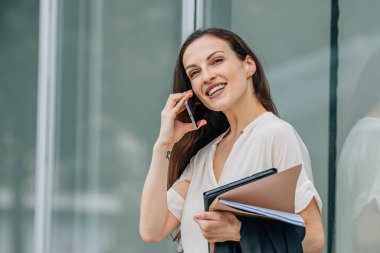 Sokakta cep telefonu ve belgeleri olan bir iş kadını.