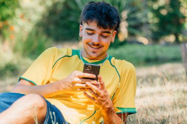 Gülümseyen genç adam cep telefonuna bakıyor.