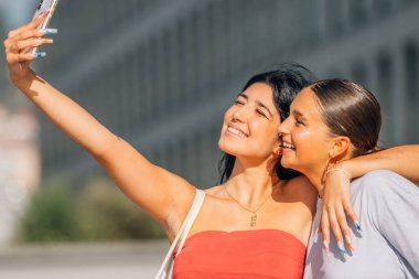 Kızlar sokakta cep telefonu kaydıyla eğleniyorlar ya da selfie çekiyorlar.