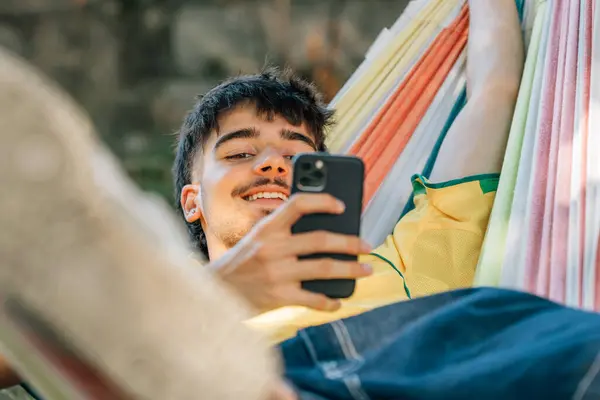 Молодий Чоловік Влітку Гамаку Відпочиває Розслаблений Мобільним Телефоном Ліцензійні Стокові Зображення