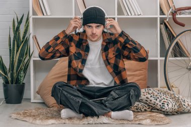 Evdeki genç adam kulaklık takıyor.